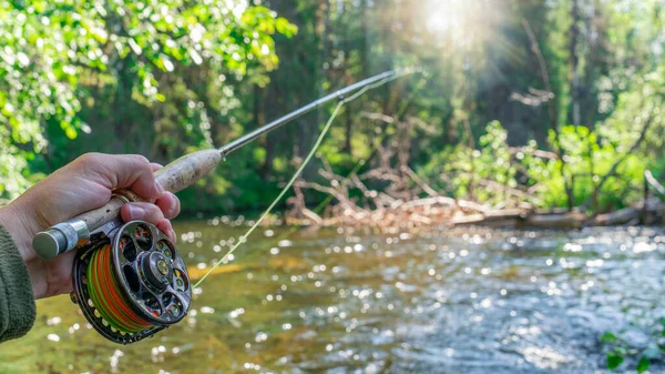 Mosca caña de pescar en la mano del pescador. Pesca en el río de montaña. Actividades de verano. — Foto de Stock
