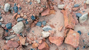 Fotoğraf kırmızı, gri renkli ve kumlu bir sürü doğal taş. Taş arkaplan.