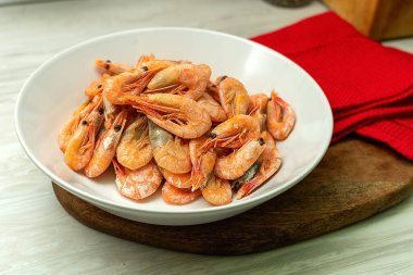 Eski beyaz ahşap masanın üzerinde beyaz bir tabakta taze karides pişirdim.