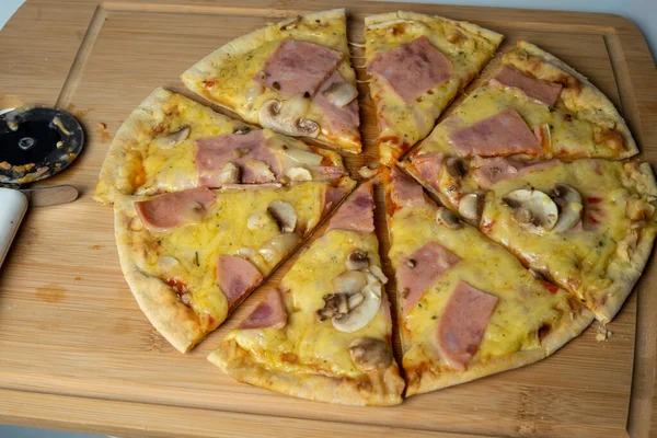 Peynirli, mantarlı ve tahtada jambonlu sulu pizza.