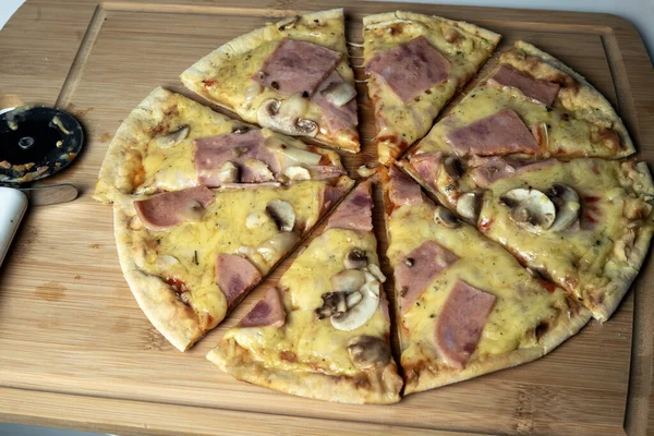 Peynirli, mantarlı ve tahtada jambonlu sulu pizza.