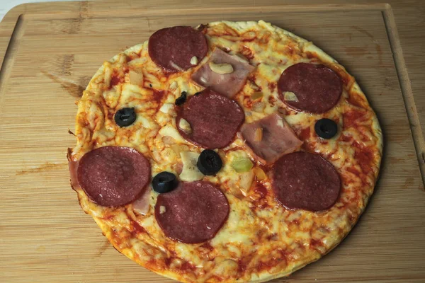 Soczysta pizza z serem i kiełbasą na drewnianej desce — Zdjęcie stockowe