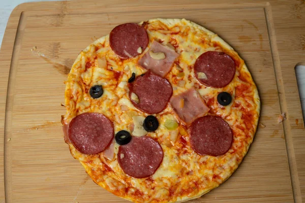 Juicy pizza with cheese and sausage on a wooden board — Stock Photo, Image