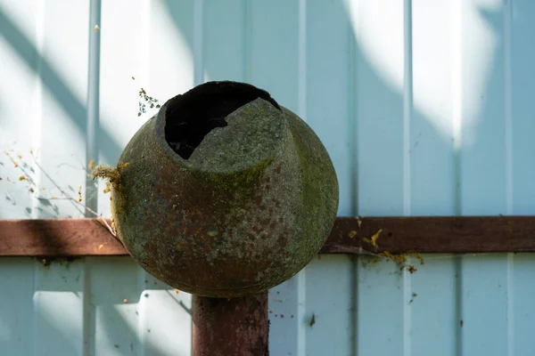 Egy rozsdás vascserép repedt fenékkel, ami a kerítésen lóg. — Stock Fotó