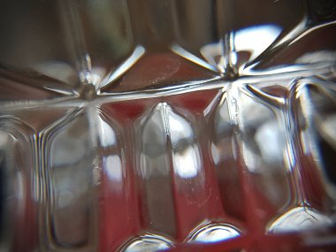 Bir camın kesiklerinden görünen kırmızı bir nesnenin ışığı.