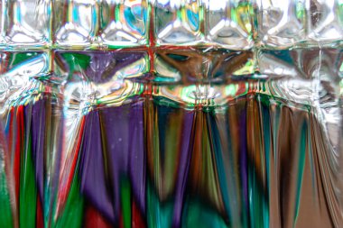 Tersine çevrilmiş viski bardağındaki desenler sayesinde ışık filoları bir elbisenin renkleri gibi görünüyor.