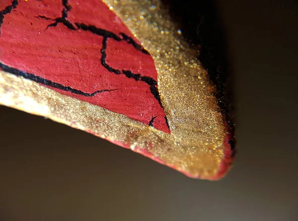 A red petal with golden borders seen very close to the object