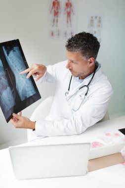 Doktor, hastasıyla video konferansı yoluyla röntgen görüntülerini tartışıyor.