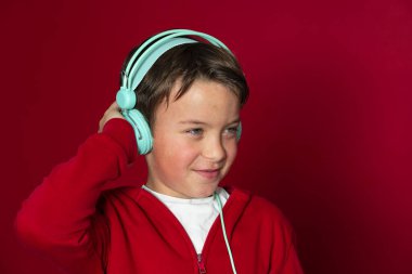 Turkuaz kulaklıklı ve kırmızı kazaklı genç havalı okul çocuğu poz veriyor.