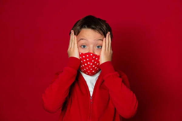 赤い背景の赤いマスクをしたかっこいい少年が赤いセーターを着て — ストック写真