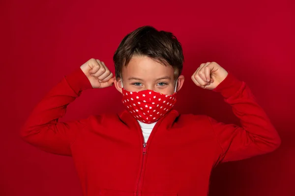 赤い背景の赤いマスクをしたかっこいい少年が赤いセーターを着て — ストック写真