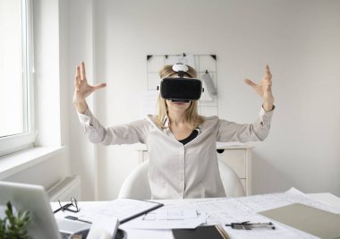 Ofisinde sanal gerçeklik gözlükleri olan genç bir kadın mimar.