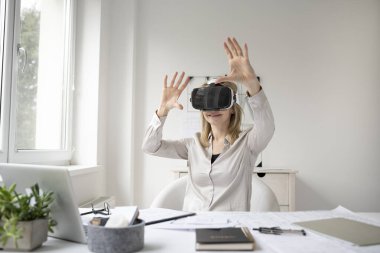 Ofisinde sanal gerçeklik gözlükleri olan genç bir kadın mimar.