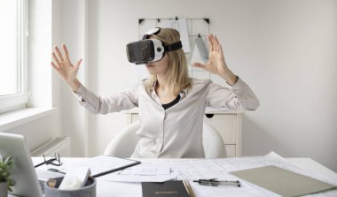 Ofisinde sanal gerçeklik gözlükleri olan genç bir kadın mimar.