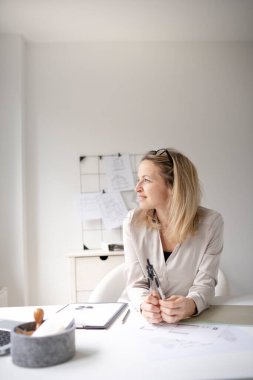 Sarışın kadın mimar ofisinde oturuyor ve Corona 'sız daha iyi zamanları hayal ediyor.