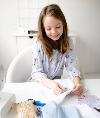 Güzel ve genç liseli kız ailesinin masasında oturmuş nakış işliyor, dikiş işliyor.