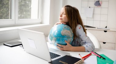 Sarışın kız dizüstü bilgisayarının önünde oturmuş elinde dünyayı tutarak tatilin ve salgının sonunu hayal ediyor.