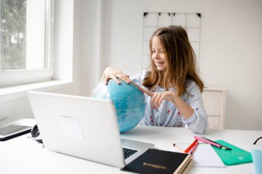 Güzel, genç, sarışın kız dizüstü bilgisayarının önünde oturmuş elinde küreyle tatilin ve salgının sonunu hayal ediyor.