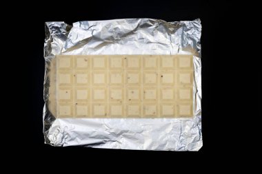 Gümüş folyo üzerine tatlı ve lezzetli çikolata. Yukarıdan çekilmiş siyah arka plan fotoğrafı.