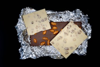 Tatlı ve lezzetli çikolatalar gümüş folyo kaplı fındıklar yukarıdan çekilmiş siyah arka plan fotoğrafları.