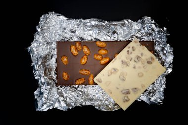 Tatlı ve lezzetli çikolatalar gümüş folyo kaplı fındıklar yukarıdan çekilmiş siyah arka plan fotoğrafları.