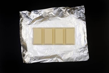 Gümüş folyo üzerine tatlı ve lezzetli çikolata. Yukarıdan çekilmiş siyah arka plan fotoğrafı.