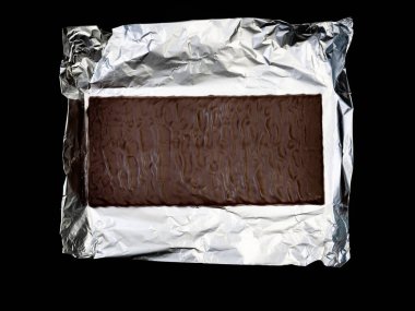 Gümüş folyo üzerine tatlı ve lezzetli çikolata. Yukarıdan çekilmiş siyah arka plan fotoğrafı.