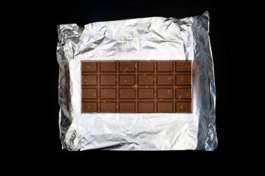 Gümüş folyo üzerine tatlı ve lezzetli çikolata. Yukarıdan çekilmiş siyah arka plan fotoğrafı.