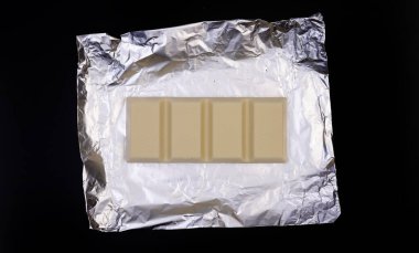 Gümüş folyo üzerine tatlı ve lezzetli çikolata. Yukarıdan çekilmiş siyah arka plan fotoğrafı.