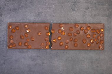 Koyu gri arka planda fındıklı çikolata, yukarıdan çekilmiş fotoğraf.