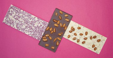 Yukarıdan çekilen pembe arkaplan fotoğrafında farklı, tatlı, narin çikolatalar.