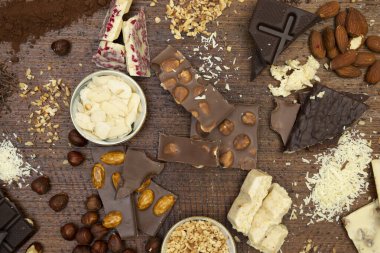 Kahverengi arka planda fındıklı ve çikolatalı bir sürü çikolata var.