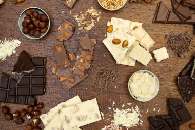 Kahverengi arka planda fındıklı ve çikolatalı bir sürü çikolata var.