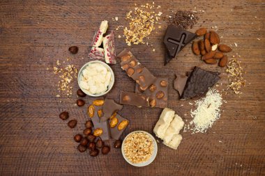 Kahverengi arka planda fındıklı ve çikolatalı bir sürü çikolata var.