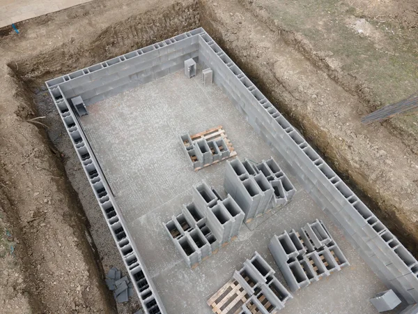 Aerial drone photo of a construction site for a pool, concrete blocks already coated and bricked up with construction adhesive