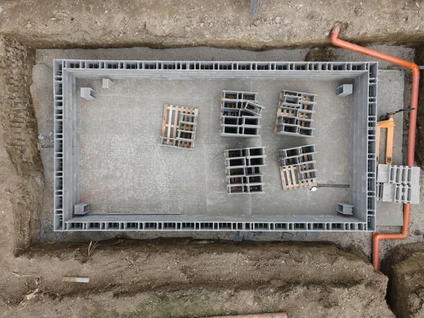 Aerial drone photo of a construction site for a pool, concrete blocks already coated and bricked up with construction adhesive