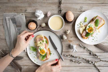 Paskalya kahvaltısı, tereyağlı ve peynirli Paskalya ekmeği, yumurta ve soğanlı jambon ve hafif ahşap arka planda Paskalya süslemesi olan fesleğen.