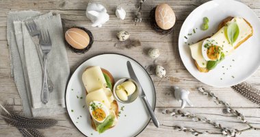 Paskalya kahvaltısı altın tostlu Paskalya çizgili ya da paskalya ekmeği tereyağlı ve peynirli hafif ahşap arka planda Paskalya süslemeli.
