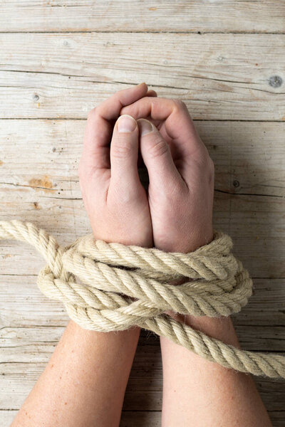 Hands of a man are tied and lie on light wooden background, addiction themed concept