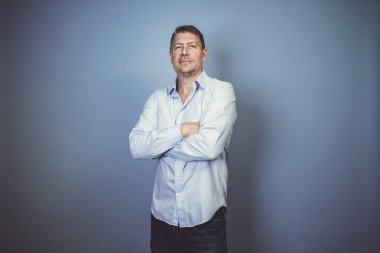 Stüdyoda mavi gömlekli orta yaşlı bir işadamı mavi arka planda poz veriyor.