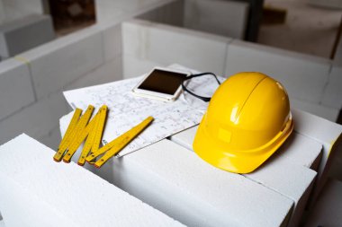 Tavan arasında diğer aletlerle birlikte inşaat alanında duran sarı koruyucu bir miğferin hayatı