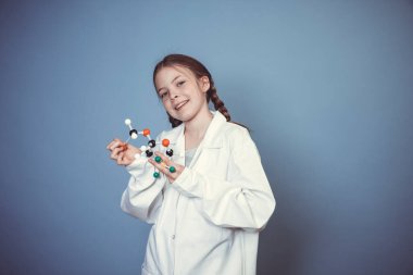 İki örgülü güzel kız bilim adamı gibi giyinmiş ve elinde mavi arka plandaki moleküllerin modelini tutuyor.