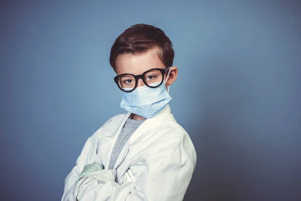 マウスガード付きのクールな男の子 スタジオで青の背景に白い研究室のコートや医師のコートと黒眼鏡とゴム手袋 — ストック写真