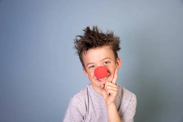 Δροσερό Αγόρι Άγρια Μαλλιά Θέτουν Κόκκινο Κλόουν Μύτη Μπλε Φόντο — Φωτογραφία Αρχείου