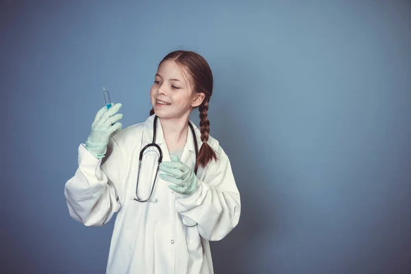青い背景の前でポーズをとる聴診器と注射器とゴム手袋を身に着けているクールな若い女の子 — ストック写真