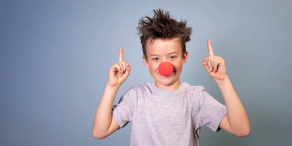 Cool Boy Dzikimi Włosami Pozowanie Czerwonym Nosem Klauna Niebieskim Tle — Zdjęcie stockowe