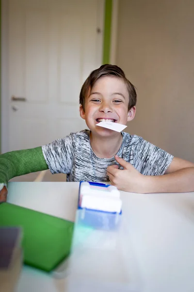 cool boy with green arm cast sits in his room and learns with flashcards