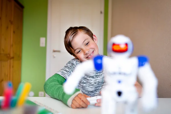 cool boy with green arm cast is sitting in his room and is playing with toy robot