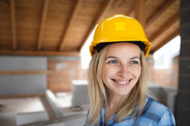 Sarı kasklı ve mavi gömlekli güzel bir bayan mimar portresi.