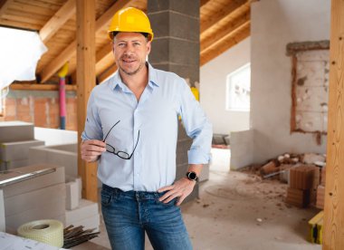 Mavi gömlekli, siyah gözlüklü, sarı kasklı ve mavi gömlekli bir erkek inşaatçı.